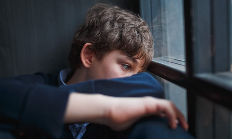 teenaged-boy-curled-up-wide-eyes-staring-out-window-768.jpg